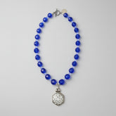 Brilliant cobalt blue takes center stage in this one-of-a-kind handcrafted Billielephante necklace. Rich, transparent faceted blue glass beads are individually separated by petite iridescent crystal-style spacers, creating exceptional sparkle as the necklace catches the light.

The strand leads to an oversized silver-tone geometric statement pendant, featuring an intricate mosaic-like reflective center and dimensional metal border. Decorative silver-tone hardware completes the eclectic artisan design.

Bold