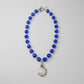 Brilliant cobalt blue takes center stage in this one-of-a-kind handcrafted Billielephante necklace. Rich, transparent faceted blue glass beads are individually separated by petite iridescent crystal-style spacers, creating exceptional sparkle as the necklace catches the light.

The strand leads to an oversized silver-tone geometric statement pendant, featuring an intricate mosaic-like reflective center and dimensional metal border. Decorative silver-tone hardware completes the eclectic artisan design.

Bold