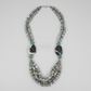 A striking one-of-a-kind handcrafted statement necklace from the Billielephante Jewelry Collection, featuring layers of natural Labradorite chips with their characteristic gray tones and subtle flashes of blue and green.

The necklace is accented with vibrant Turquoise beads, ornate German silver-tone components, and dramatic faceted Tiger Agate stones. Multiple strands of irregular Labradorite create wonderful texture and movement, while the oversized dark stones and detailed silver-tone spacers give the p