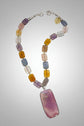 A collection of smooth rectangular agate-style stone beads travels around the necklace in shades of lavender, smoky blue-gray, translucent blush, honey amber and golden yellow. Each bead displays its own variations in color and pattern, creating the collected, globally inspired character that defines the Billielephante collection.
